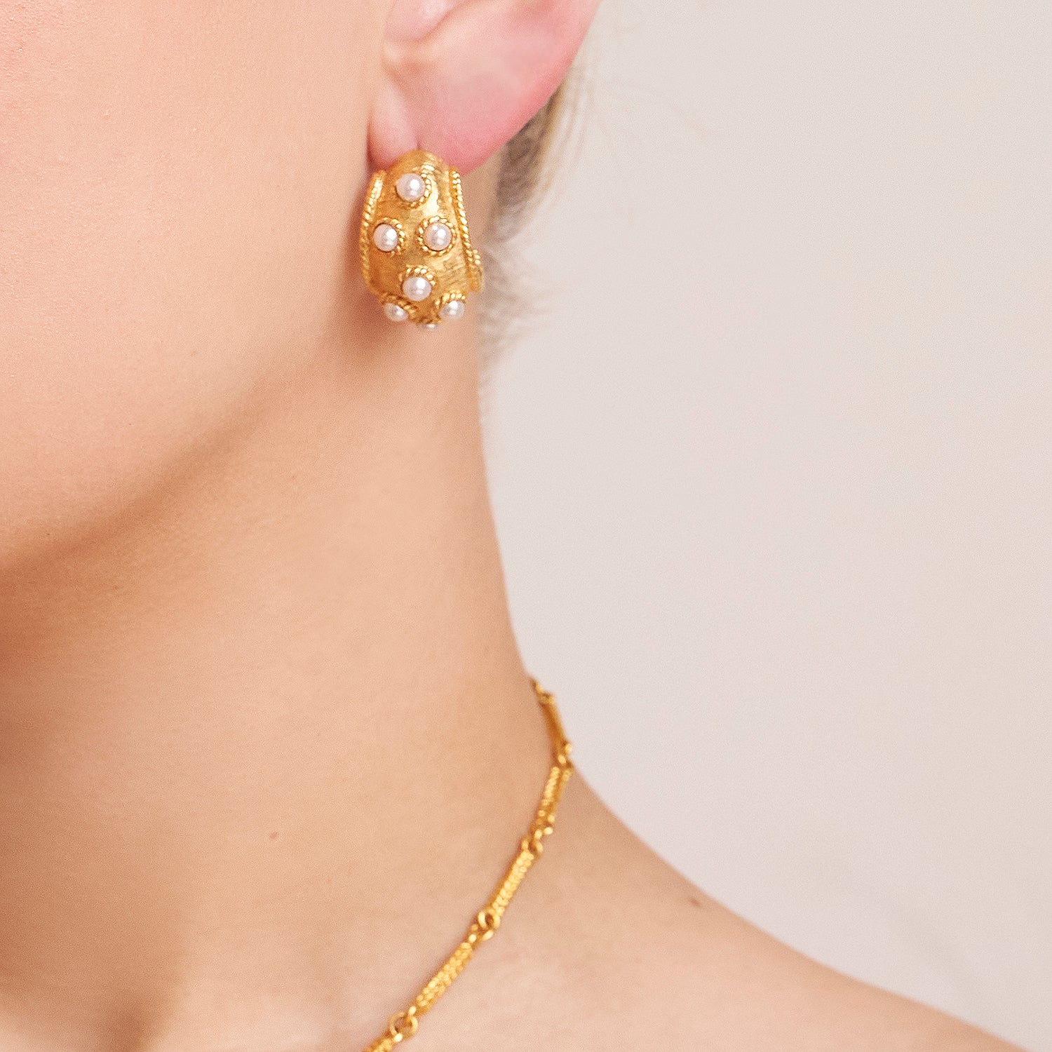 model wearing gold post earrings with majorca pearls and thin gold necklace